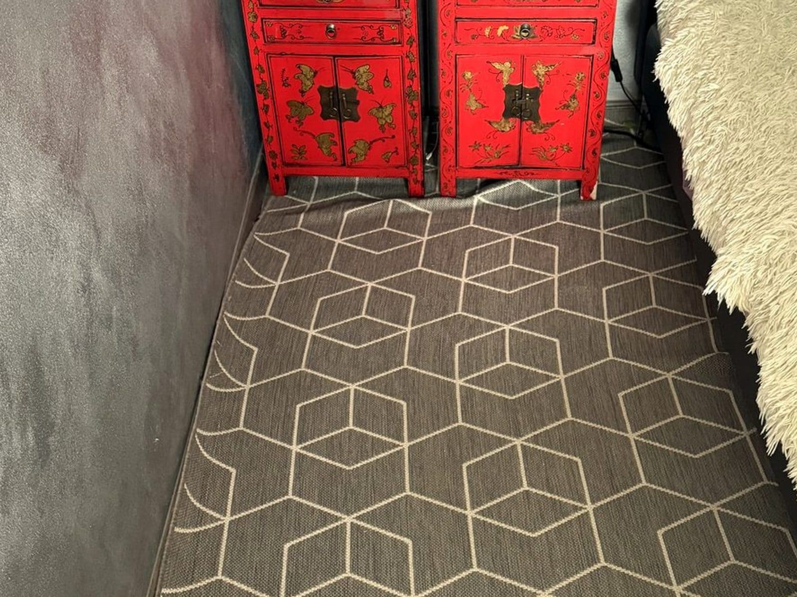Washable rugs for living room inspiration: gray flat-woven rug with a cream geometric pattern in a small room beside two red lacquered nightstands